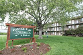 Westminster apartment for rent - A sign for Candlelight Apartments stands in front of a tree and apartment building.