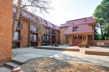 Boulder apartment for rent - A red brick building with a red roof and a courtyard in front.