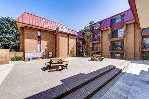 Boulder condo for rent - two picnic tables on a wooden deck in front of two brick buildings