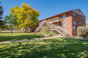 Lakewood apartment for rent - A tree with yellow leaves is in front of a red brick building.