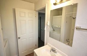 Denver apartment for rent - A white bathroom with a sink, mirror, and a door.