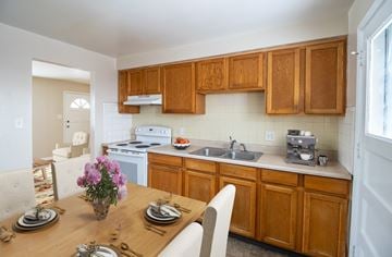 Denver apartment for rent - A kitchen with wooden cabinets and a dining table set for two.