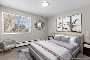 Denver apartment for rent - A bedroom with a large bed, a chair, and a window with a view of a tree-lined street.