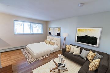 Denver apartment for rent - A living room with a brown couch and a white bed.