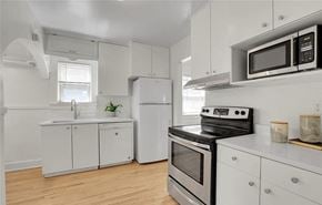 Denver apartment for rent - a kitchen with white cabinets and a stove and a microwave
