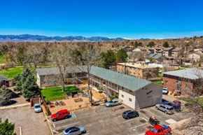 Arvada apartment for rent - A parking lot with cars and a building in the background.