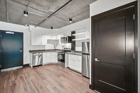 Greeley apartment for rent - a kitchen with white cabinets and stainless steel appliances and a black door