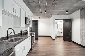 Greeley apartment for rent - a kitchen with white cabinets and stainless steel appliances and a black door