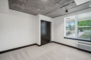 Greeley apartment for rent - an empty living room with a large window and a door to a hallway