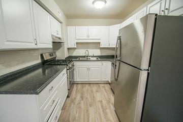 Longmont apartment for rent - a kitchen with white cabinets and a stainless steel refrigerator
