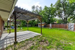 Boulder triplex for rent - A patio with a pergola and a carport is surrounded by a grassy area and trees.