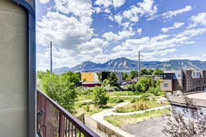 Boulder apartment for rent - A view from a balcony overlooking a parking lot with mountains in the distance.