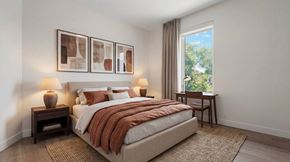 Denver apartment for rent - A bedroom with a large bed and a window showing trees outside.