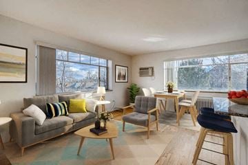 Denver apartment for rent - A living room with a grey couch, a wooden coffee table, and a dining table with chairs.