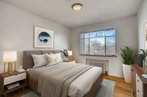 Denver apartment for rent - A bedroom with a large bed and a window with a view of trees outside.