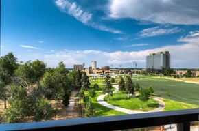 Denver apartment for rent - A view of a cityscape from a balcony with buildings, trees, and a clear sky.at Peregrine Place Apartments, Denver, CO 80246