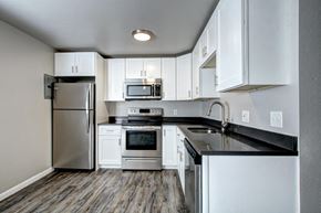 Arvada apartment for rent - a kitchen with white cabinets and stainless steel appliances