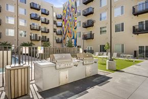 Aurora apartment for rent - A colorful mural on a building behind a patio with a grill and a hot tub.