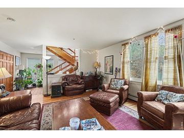 Boulder apartment for rent - A living room with brown leather furniture and a staircase in the background.