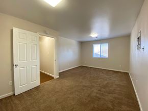 Commerce City apartment for rent - A room with a carpeted floor and a door leading to another room.