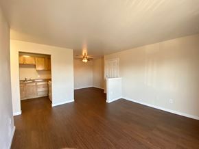 Commerce City apartment for rent - A room with wooden floors and a kitchen area in the background.
