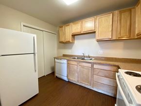 Commerce City apartment for rent - A kitchen with a white refrigerator, wooden cabinets, and a white stove top oven.