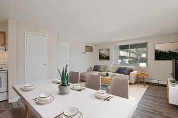 Westminster apartment for rent - A dining table set with plates and cutlery is in the foreground of a modern kitchen and living room.