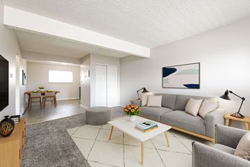 Arvada apartment for rent - A living room with a grey couch, a white coffee table, and a painting on the wall.