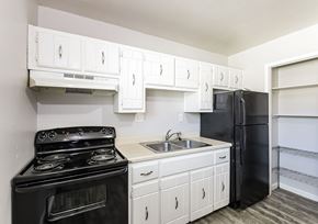 Arvada apartment for rent - A black stove and oven in a kitchen with white cabinets.