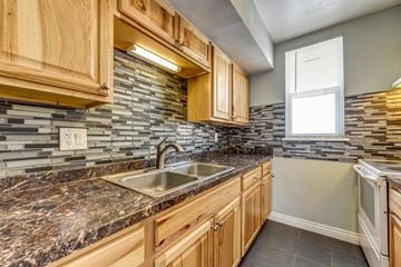 Lafayette townhouse for rent - a kitchen with wood cabinets and granite counter tops and a sink