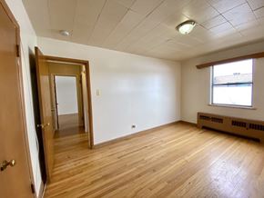 Denver apartment for rent - A room with wooden floors and a window with blinds.
