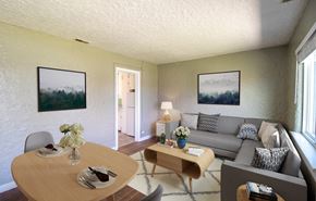 Wheat Ridge apartment for rent - A living room with a grey couch, a wooden table, and two framed pictures on the wall.