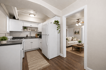 Denver apartment for rent - A kitchen with white cabinets and a black countertop with a rug on the floor.