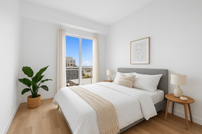 Denver apartment for rent - A bedroom with a large bed, a potted plant, and a window overlooking a cityscape.