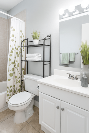 Denver apartment for rent - A white bathroom with a toilet, sink, and a mirror.