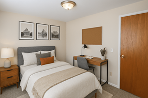 Denver apartment for rent - A bedroom with a bed, desk, and pictures on the wall.