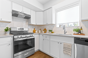 Denver apartment for rent - A white kitchen with a stove, sink, and cabinets.