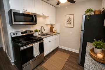 Denver apartment for rent - A modern kitchen with a black stove top oven and white cabinets.