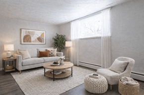 Englewood apartment for rent - A living room with a grey couch, a white armchair, and a coffee table.
