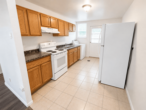 Denver apartment for rent - A kitchen with white appliances and wooden cabinets.