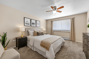 Denver apartment for rent - A bedroom with a large bed, a ceiling fan, and a chair.