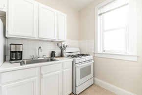 Denver apartment for rent - A white kitchen with a stove, sink, and cabinets.