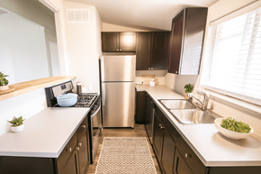 Denver apartment for rent - A modern kitchen with a stainless steel refrigerator and a sink with a bowl of green vegetables on the counter.