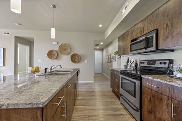 Fort Collins apartment for rent - A modern kitchen with wooden cabinets and a granite countertop.