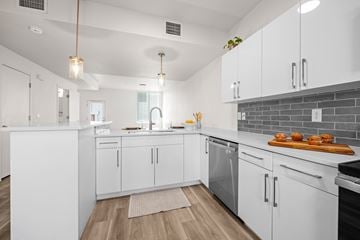 Boulder apartment for rent - A modern kitchen with white cabinets and a wooden floor.