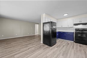 Denver apartment for rent - A black fridge stands in a kitchen with wooden floors and white walls.