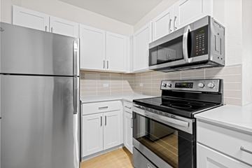Denver apartment for rent - A kitchen with a refrigerator, microwave, oven and cabinets.