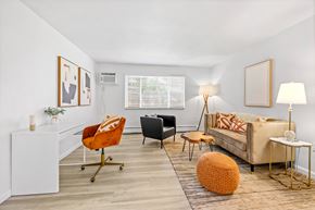 Englewood apartment for rent - A living room with a white couch, a black chair, and a white side table.