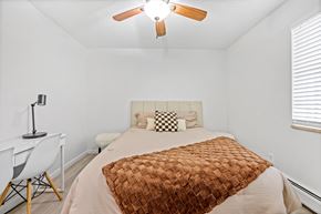 Englewood apartment for rent - A bedroom with a bed, chair, and ceiling fan.