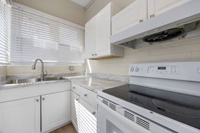 Denver apartment for rent - A white kitchen with a stove, sink, and cabinets.